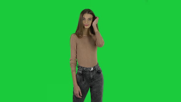 Slender Girl with Long Hair Is Posing and Smiling on a Green Screen