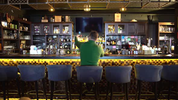 a Man Sits Behind a Bar and Takes a Selfie