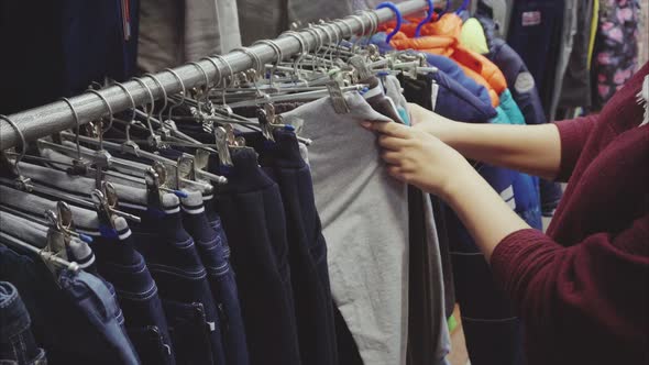 Woman Hand Chooses a Pants for the Boy in the Second Hand Shop