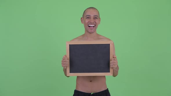 Happy Bald Multi Ethnic Shirtless Man Holding Blackboard and Looking Surprised