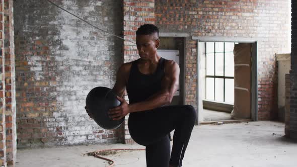 African american man exercising with medicine ball in an empty urban building