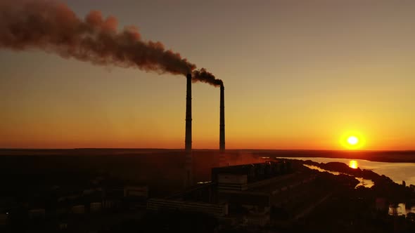 Smokestack in factory with yellow cloudless sky