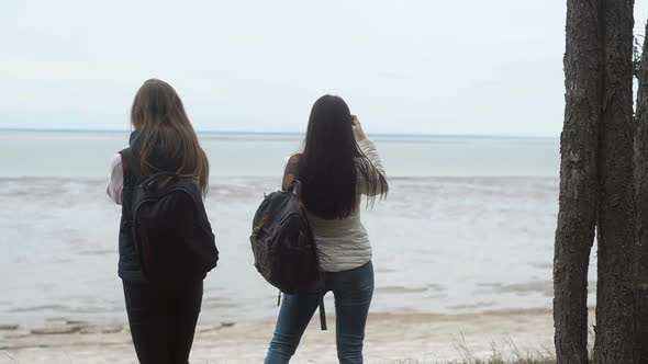 Two girls edge cliff and shoot landscapes with phone camera create Fun selfies