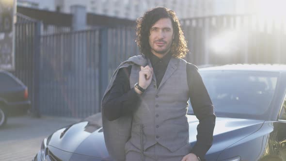 Medium Shot Portrait of Successful Confident Man Hanging Blazer on Shoulder in Slow Motion Looking