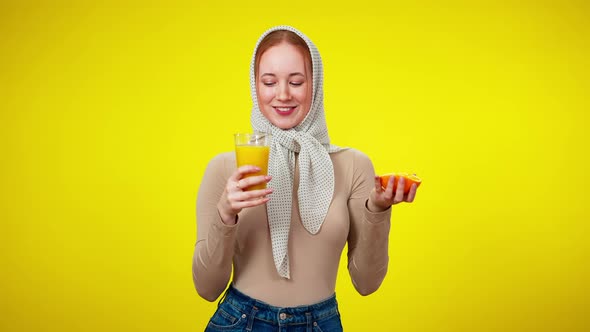 Middle Shot of Charming Beautiful Young Woman Holding Juice Glass and Half of Orange Looking at