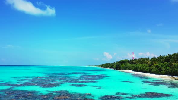 Tropical flying tourism shot of a paradise sunny white sand beach and blue water background 