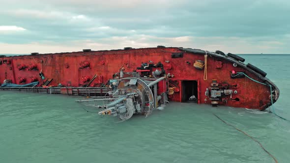 Cargo Ship Lies on Its Side, Near the Shore of a Sandy Beach with a Barrier To the Pollution Zone