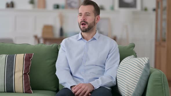 Sick Young Man Sneezing Sitting on Sofa