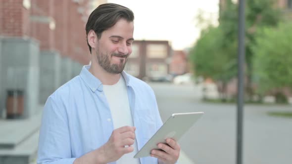 Man Celebrating on Tablet While Standing Outdoor