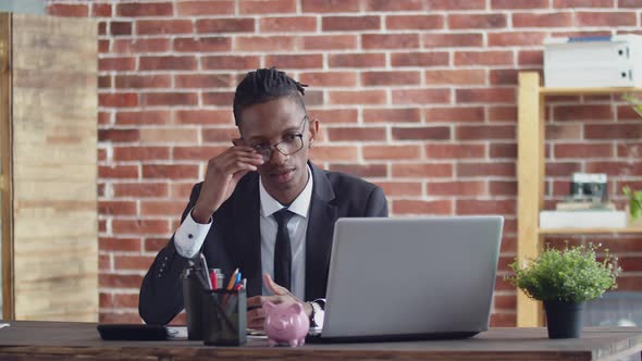 Disgruntled Black Man Speaks Angry on Video Link on a Laptop in the Office at the Work Table