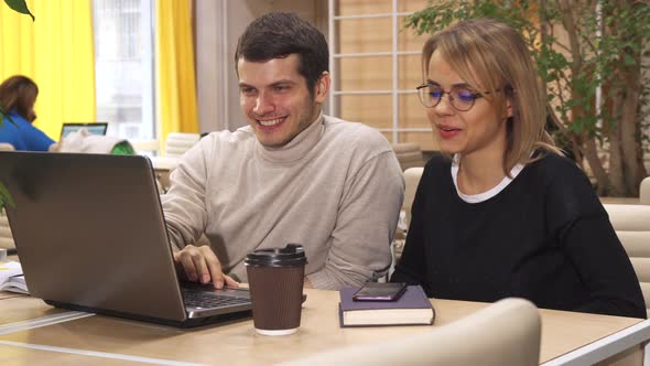 Young Woman Shows the Guy Something on Her Phone at the Working Hub