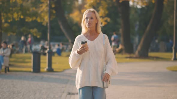 Happy Senior Woman Walking with Takeaway Coffee Cup Walking Park