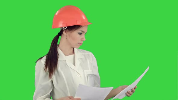 Female Engineer in Helmet Reading Contract and Nodding Her Head on a Green Screen, Chroma Key