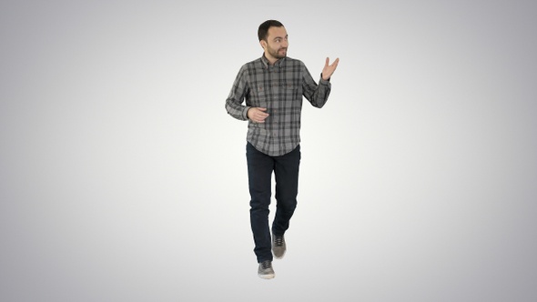 Young confident man in shirt and jeans walking towards