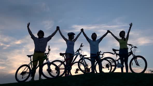 Young Cyclists Holding Hands at Sunset