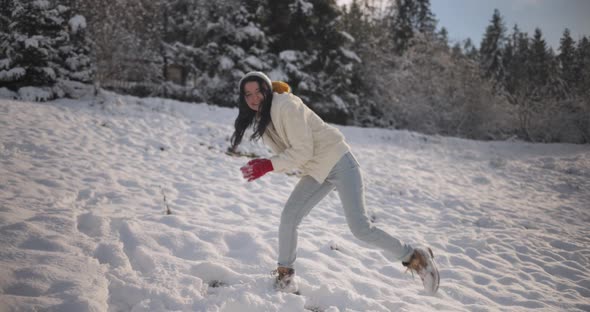 Woman Playing Winter Game Throwing Snowball in Mountain Forest Outdoors