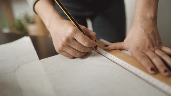 unrecognizable tailor using ruler near sewing machine in workshop