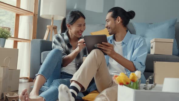 asian young attractive couple man and woman sit at new home drink coffee relax and talk smile.