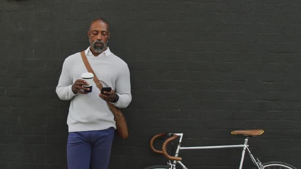 African American man drinking a coffee and using his phone
