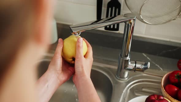 Person Washing Sweet Quince Fruit with Tap Water