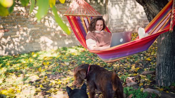 A Young Adult Woman Freelancer Working on a Laptop While Lying in a Hammock
