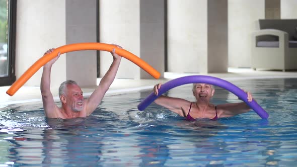 Joyful Mature Couple Exercising in Water of Pool