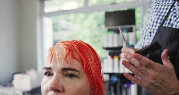 Front view woman having her hair styled by a hairdresser