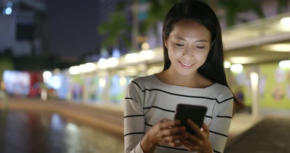 Woman use of smart phone in city at night 