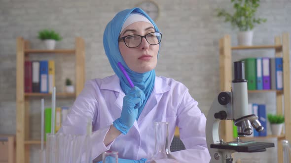 Thoughtful Young Muslim Woman Scientist Chemist in National Scarf Working in the Lab
