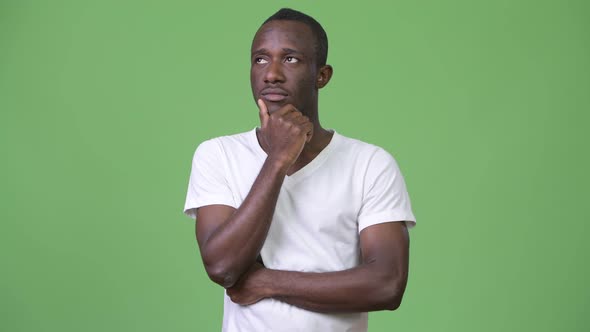 Young African Man Thinking Against Green Background