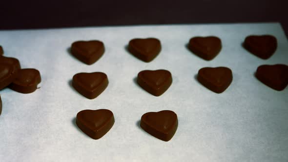 Worker arranging heart shaped dark chocolate on tray