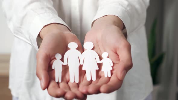 Closeup Female Hands Holding A Family Illustrated In Paper Silhouette. Family Silhouette Of People