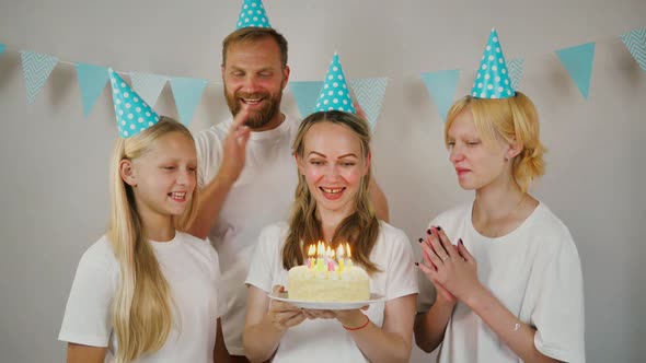 a Young Mother with Her Daughters and Her Husband Celebrates a Birthday Blows Out the Candles on the