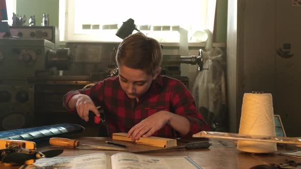 A Teenager Works with a Stationery Knife and a File