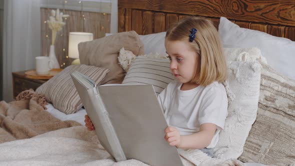 Little Cute Girl Small Daughter Kid Child Baby Toddler Preschooler Sits in Bed in Cozy Bedroom