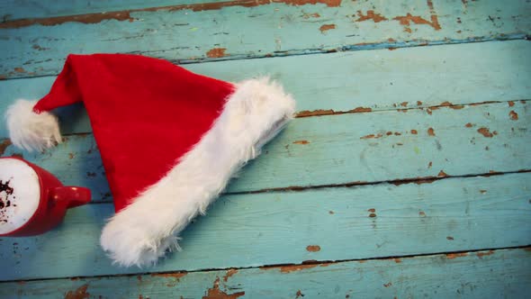 Santa hat and coffee mug on wooden plank