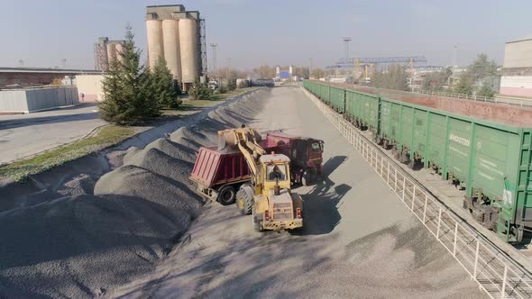 Front Loader Loads Gravel Into Dump Truck Body at Construction Logistics Hub