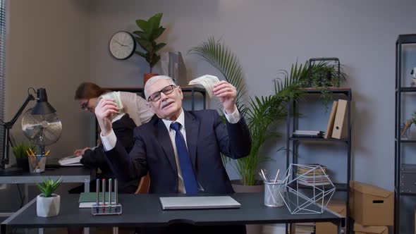 Elderly Man Boss Celebrating Business Success Dancing with Money Dollar Cash in Modern Office Room