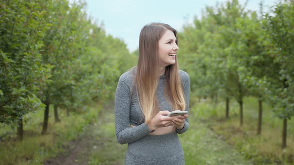 Happy Woman Typing By Mobile Phone Outdoors