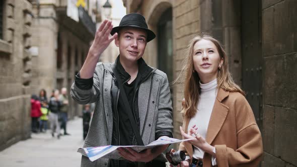 Two Stylish Friend Standing at the Street and Look for Something Using a Map