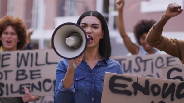 Diverse group of men and women holding placards shouting using megaphone during protest