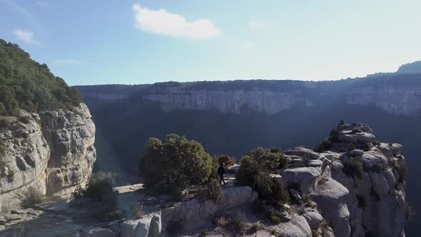 Aerial view of man walking towards cliff edge at great height, tracking shot