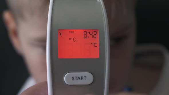 Dad Taking Sons Temperature Using a Digital Thermometer Covid 19 Virus Symptom, display 37.8 Degrees