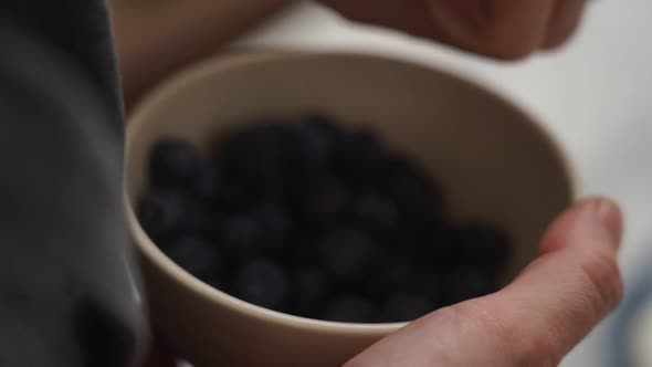 Crop confectioner decorating yummy creamy cake with blueberries