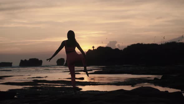 Back View of Young Caucasian Woman Doing Gymnastics Exercises on the Beach