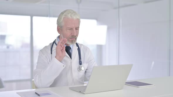 Cheerful Old Senior Doctor Doing Video Chat on Laptop