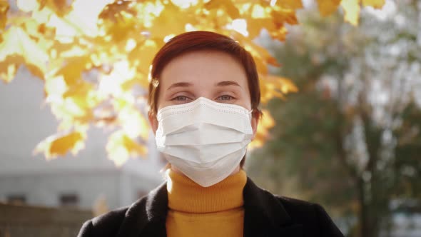 Portrait of a Beautiful Young Woman Wearing Protective Medical Mask and Standing on the Street
