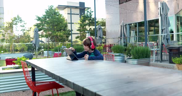 A young boy attempts to learn remotely on his laptop and headphones over distance learning due to th