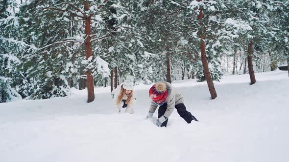 Outdoor family fun on Christmas vacation. Boy and girl play snowballs. Winter clothing. Slow motion.