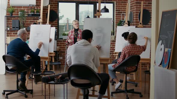 Senior Teacher Supervising Students to Draw Vase Model on Canvas